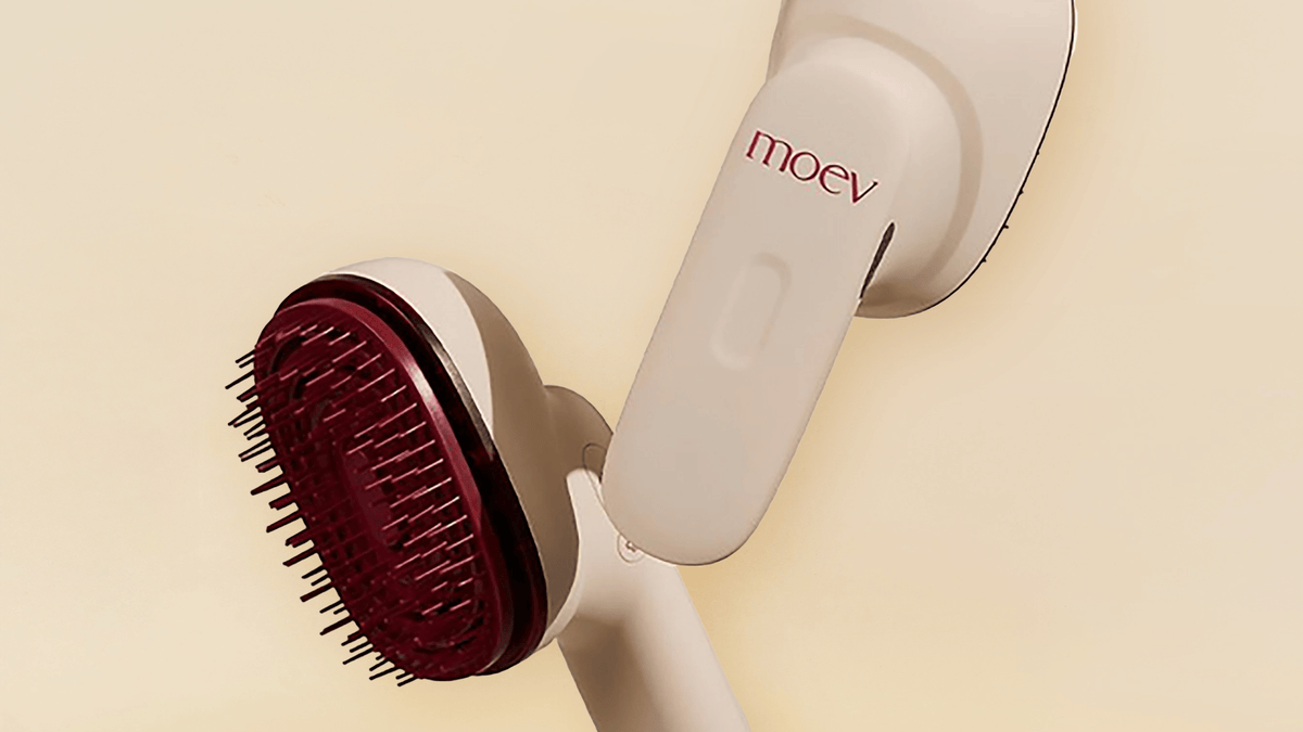 MOEV Hair Steamer Pro med röd borstyta mot beige bakgrund. Innovativ hårvårdsborste med ånga och LED-ljus som ger glans och vårdar hårbotten.