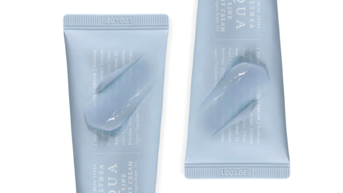 En person håller en rosa tub av Beauty of Joseon ansiktsolja mot sin axel, med en neutral bakgrund.