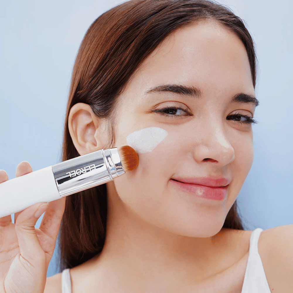Malli levittää ELROEL Blanc Cover Cream Stick concealer poskelle sisäänrakennetulla harjalla luonnollisen ja tasaisen peittävyyden saamiseksi.