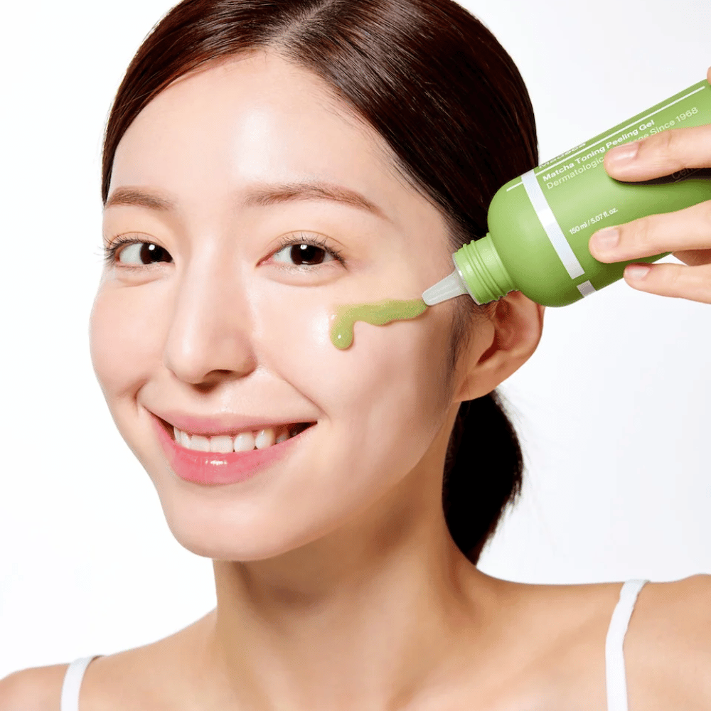 Henkilö, joka levittää Centellian24 Madeca Matcha Toning Peeling Gel – mieto kasvojen kuorinta, joka auttaa poistamaan kuolleita ihosoluja ja tekemään ihosta pehmeämmän ja säteilevämmän.