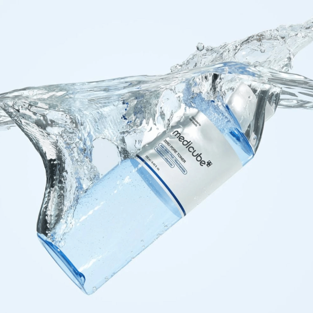 Medicube Zero Pore Toner 250 ml, kuoriva kasvovesi, jossa on AHA:ta, BHA:ta ja PHA:ta. Läpinäkyvä sininen pullo suuren vesiroiskeen ympäröimänä.
