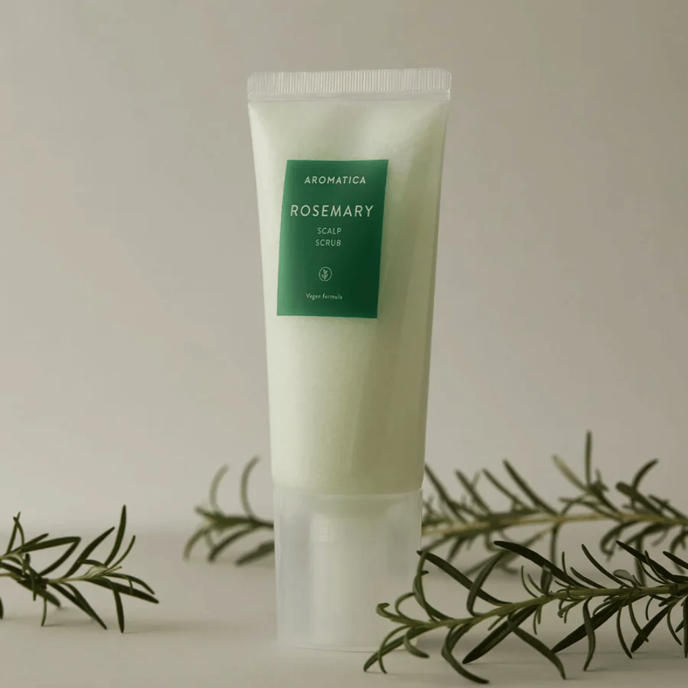 2. AROMATICA Rosemary Scalp Scrub 165 g – päänahan kuorinta vaaleanvihreässä tuubissa rosmariininoksien kanssa beigeä taustaa vasten
